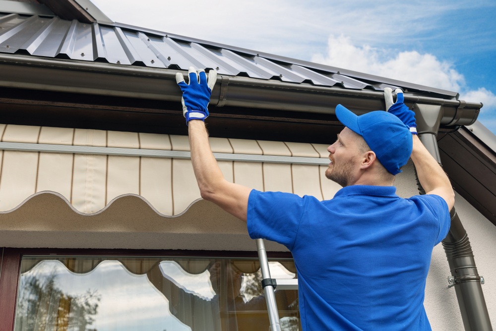 plumber-installing-rain-gutter-system-on-house-roof