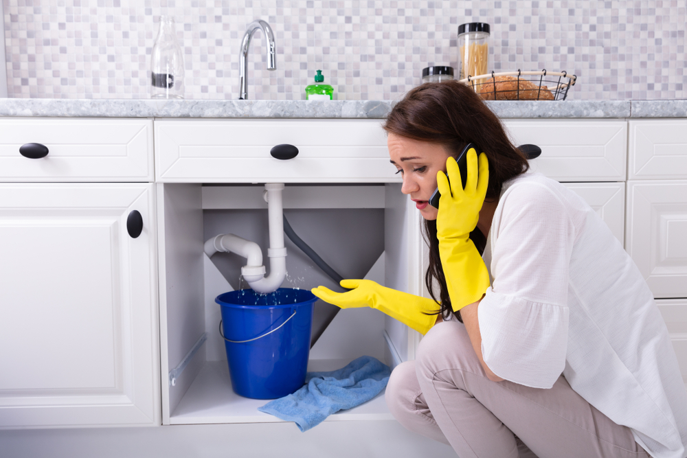 girl-on-phone-to-plumber-leaking-kitchen-sink
