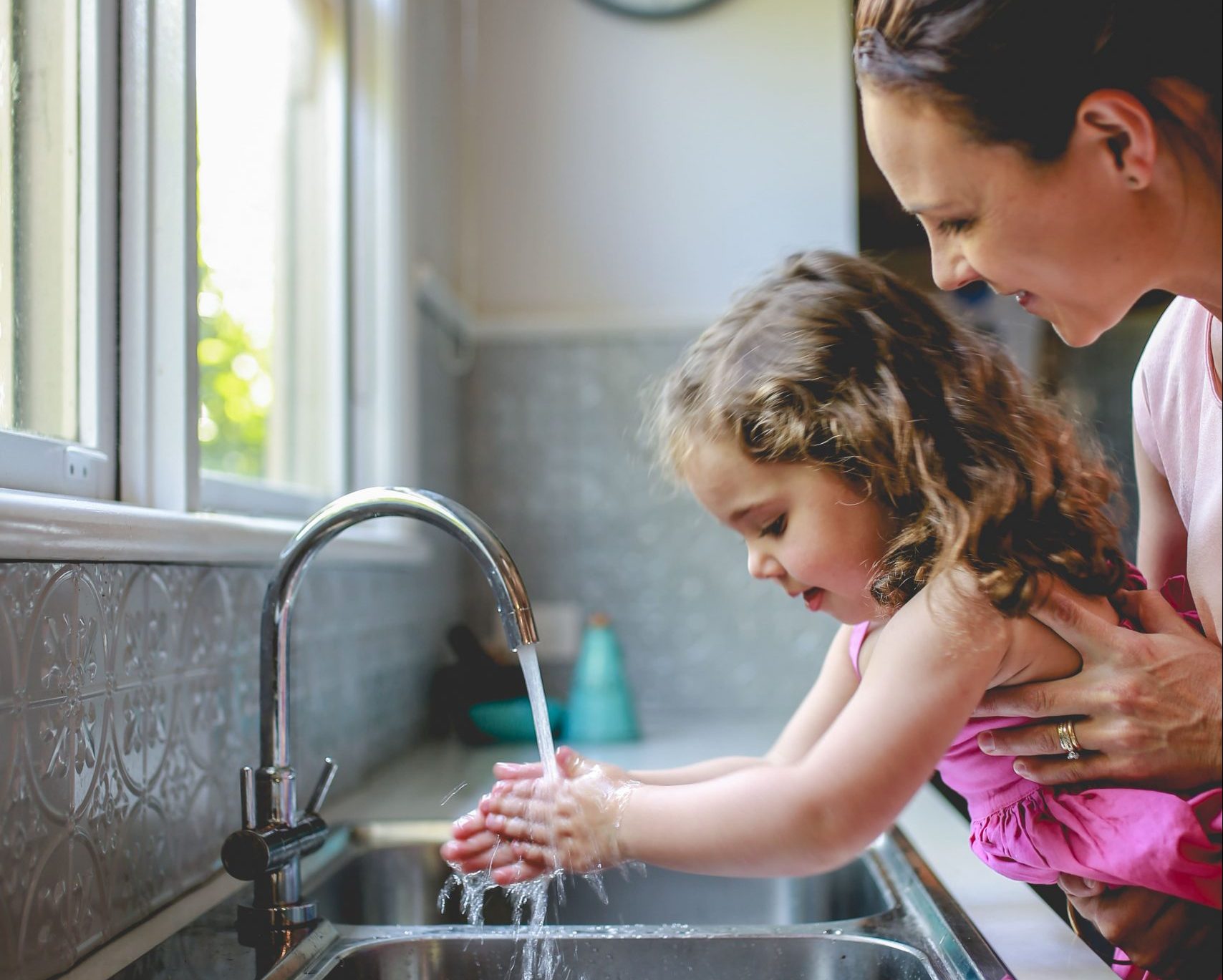 mother-helping-daughter-wash-hands